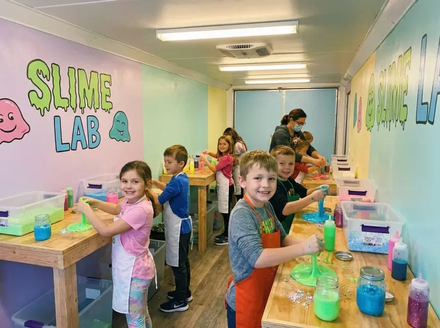 Kids making slime at hands-on stations inside the Slime Lab trailer